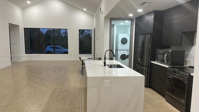 14074 Whittier Prt, Charlotte, FL 33981 - kitchen featuring black appliances, dark cabinetry, modern cabinets, a sink, and stacked washer / dryer