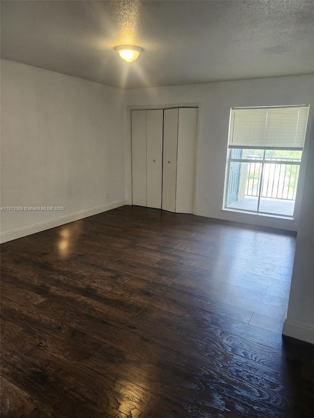 833 Riverside Dr Unit 834, Coral Springs, FL 33071 - unfurnished bedroom featuring a textured ceiling, dark wood-style floors, baseboards, and a closet