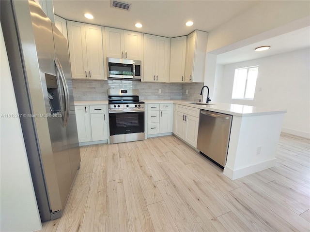 4579 NW 16th Way, Tamarac, FL 33309 - kitchen featuring stainless steel appliances, a sink, light wood-style flooring, a peninsula, and backsplash