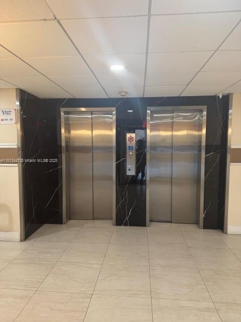 4550 NW 9th St Unit 520E, Miami, FL 33126 - hallway featuring elevator, light tile patterned floors, and a paneled ceiling