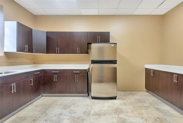 4001 S Ocean Dr Unit 14H, Hollywood, FL 33019 - kitchen with freestanding refrigerator, light countertops, baseboards, dark brown cabinets, and a paneled ceiling