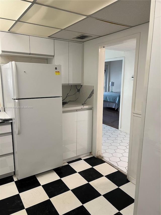 3475 S Ocean Blvd Unit 1130, Palm Beach, FL 33480 - kitchen with freestanding refrigerator, white cabinetry, light countertops, light flooring, and a drop ceiling