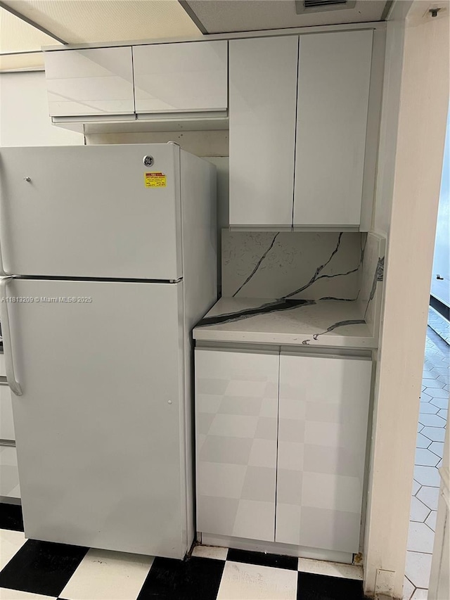 3475 S Ocean Blvd Unit 1130, Palm Beach, FL 33480 - kitchen with freestanding refrigerator, tile patterned floors, and white cabinetry