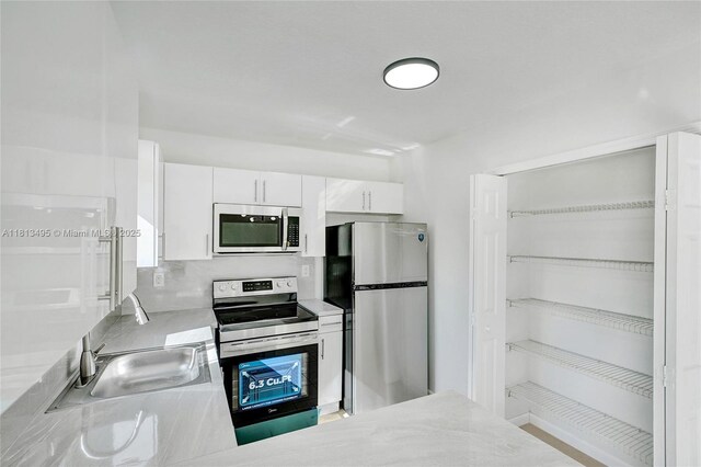3398 NE 9th Dr Unit 104, Homestead, FL 33033 - kitchen featuring stainless steel appliances, light countertops, white cabinets, a sink, and backsplash