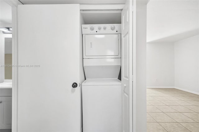 3398 NE 9th Dr Unit 104, Homestead, FL 33033 - washroom featuring stacked washing machine and dryer, light tile patterned flooring, and baseboards