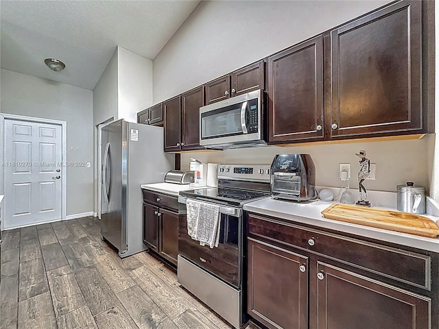 6142 NW Hopkins Ave, Port St Lucie, FL 34986 - kitchen featuring stainless steel appliances, dark brown cabinets, wood finished floors, and light countertops