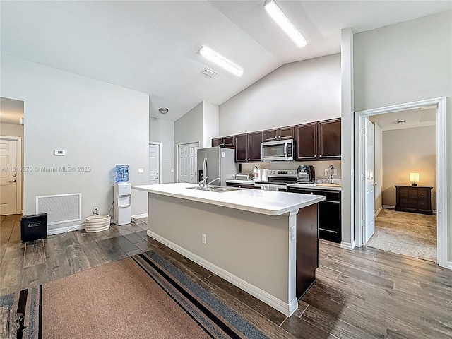 6142 NW Hopkins Ave, Port St Lucie, FL 34986 - kitchen featuring stainless steel appliances, an island with sink, dark wood-style flooring, dark brown cabinets, and light countertops