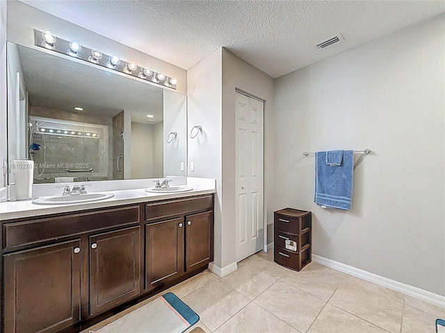 6142 NW Hopkins Ave, Port St Lucie, FL 34986 - full bathroom with double vanity, a stall shower, a textured ceiling, baseboards, and tile patterned flooring