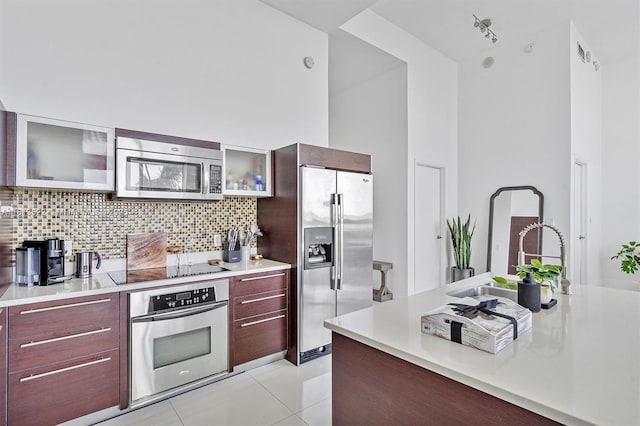 1900 N Bayshore Dr Unit 603, Miami, FL 33132 - kitchen with appliances with stainless steel finishes, modern cabinets, light countertops, backsplash, and glass insert cabinets