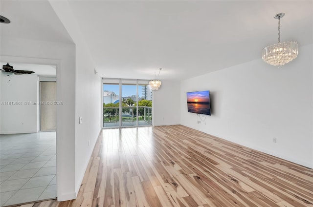 3330 NE 190th St Unit 416, Aventura, FL 33180 - unfurnished living room featuring a chandelier, a wall of windows, ceiling fan, and light wood-style flooring