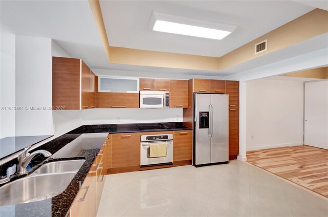 3330 NE 190th St Unit 416, Aventura, FL 33180 - kitchen with appliances with stainless steel finishes, a sink, brown cabinetry, and dark stone counters