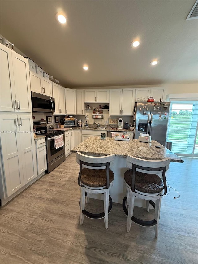3031 Cherry Ln, La Belle, FL 33935 - kitchen featuring stainless steel appliances, a breakfast bar, recessed lighting, light wood-type flooring, and white cabinetry