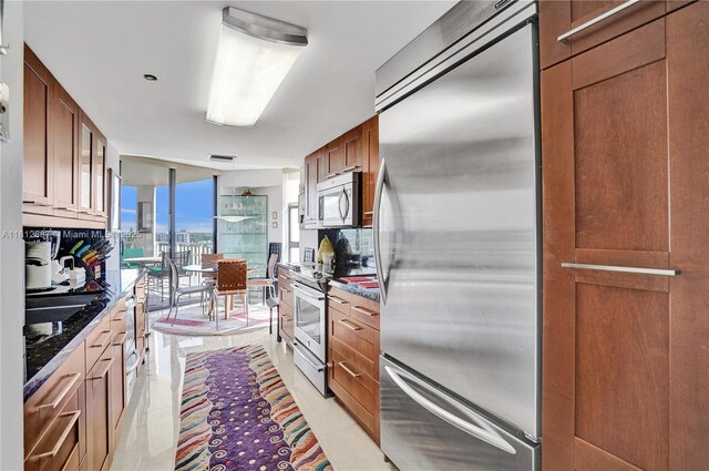 1000 Quayside Ter Unit 1101, Miami, FL 33138 - kitchen featuring stainless steel appliances, light tile patterned floors, glass insert cabinets, dark stone counters, and expansive windows