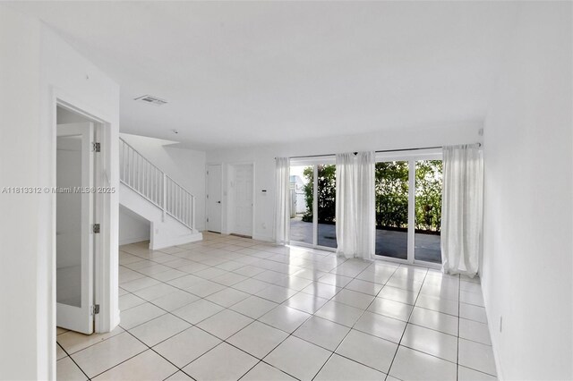 7342 Gary Ave, Miami Beach, FL 33141 - spare room with stairway, light tile patterned floors, and baseboards