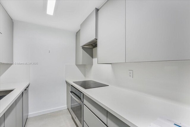1865 79th St Unit 12G, North Bay Village, FL 33141 - kitchen with stainless steel oven, black electric stovetop, gray cabinetry, and light countertops
