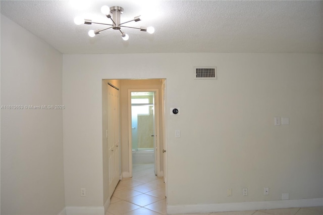 705 NE 2nd St Unit 4, Hallandale Beach, FL 33009 - empty room with a chandelier, light tile patterned flooring, a textured ceiling, and baseboards