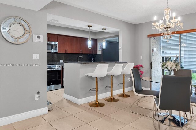 8401 SW 107th Ave Unit 117E, Miami, FL 33173 - kitchen featuring appliances with stainless steel finishes, backsplash, a chandelier, light tile patterned floors, and baseboards
