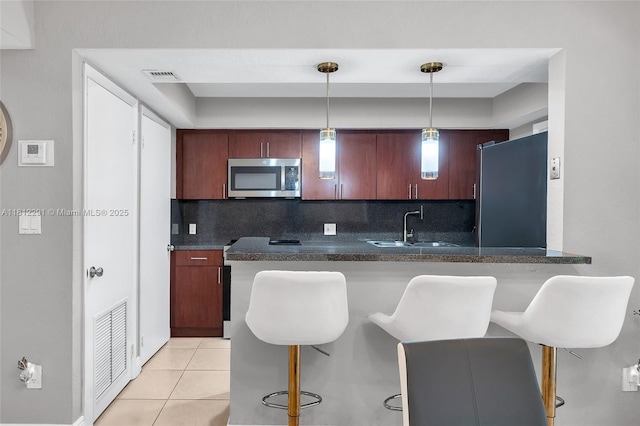 8401 SW 107th Ave Unit 117E, Miami, FL 33173 - kitchen featuring stainless steel appliances, a sink, decorative backsplash, dark countertops, and a breakfast bar area