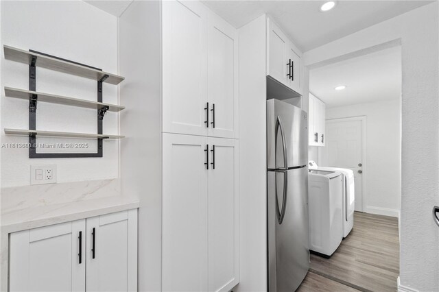 2374 NW 56th St, Miami, FL 33142 - kitchen featuring freestanding refrigerator, baseboards, white cabinetry, washer and clothes dryer, and light wood-type flooring