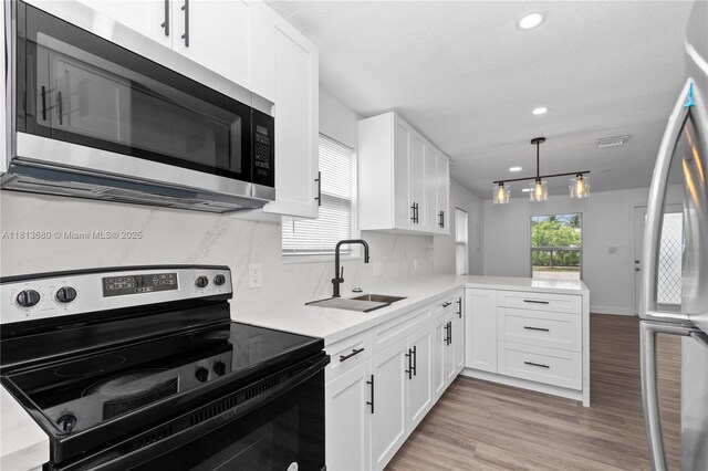 2374 NW 56th St, Miami, FL 33142 - kitchen with appliances with stainless steel finishes, a sink, light wood-style flooring, light countertops, and a peninsula