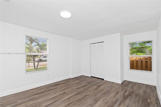 2374 NW 56th St, Miami, FL 33142 - unfurnished bedroom featuring wood finished floors, multiple windows, baseboards, and a closet