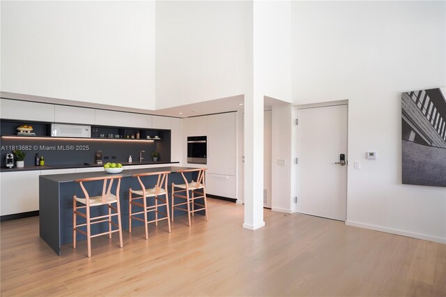10250 Collins Ave Unit Ph1, Bal Harbour, FL 33154 - bar with wall oven, white microwave, light wood finished floors, a high ceiling, and baseboards