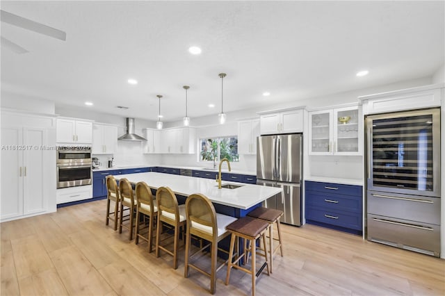 3229 Canal Dr, Pompano Beach, FL 33062 - kitchen featuring appliances with stainless steel finishes, wall chimney exhaust hood, blue cabinetry, wine cooler, and a breakfast bar area