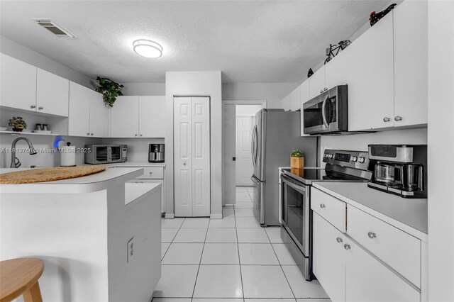 14011 SW 151st Ave, Miami, FL 33196 - kitchen with appliances with stainless steel finishes, light countertops, a textured ceiling, white cabinets, and light tile patterned floors