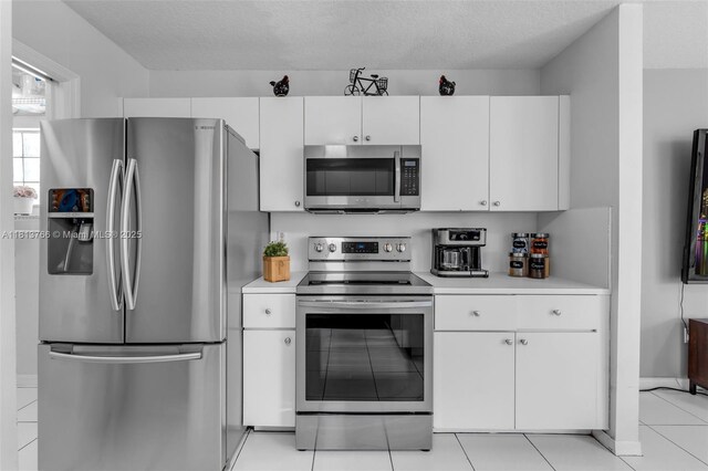 14011 SW 151st Ave, Miami, FL 33196 - kitchen with stainless steel appliances, light countertops, white cabinetry, light tile patterned floors, and a textured ceiling