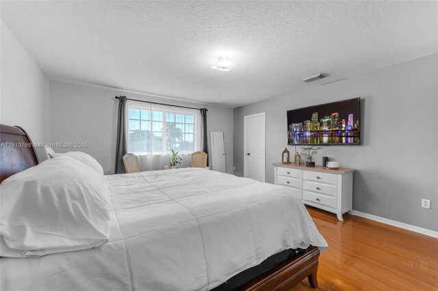 14011 SW 151st Ave, Miami, FL 33196 - bedroom with light wood-style floors, a textured ceiling, and baseboards