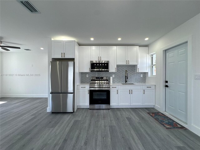 5450 SW 6th St, Miami, FL 33134 - kitchen with appliances with stainless steel finishes, a sink, wood finished floors, light countertops, and white cabinets