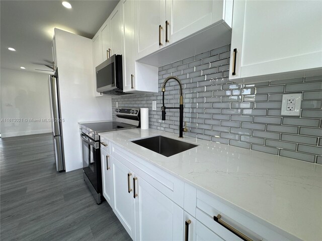 5450 SW 6th St, Miami, FL 33134 - kitchen with stainless steel appliances, a sink, white cabinets, dark wood-style floors, and decorative backsplash