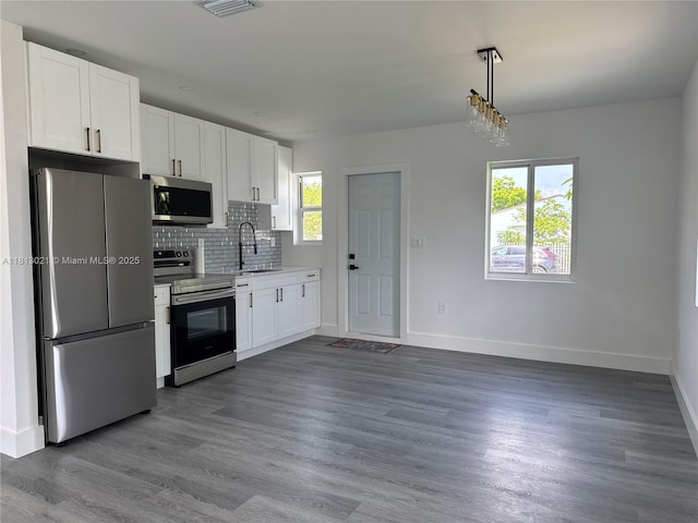 5450 SW 6th St, Miami, FL 33134 - kitchen featuring stainless steel appliances, baseboards, decorative backsplash, white cabinets, and dark wood-style floors