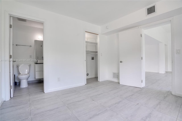 1201 S Biscayne Point Rd, Miami Beach, FL 33141 - unfurnished bedroom with light tile patterned flooring, a walk in closet, connected bathroom, and baseboards