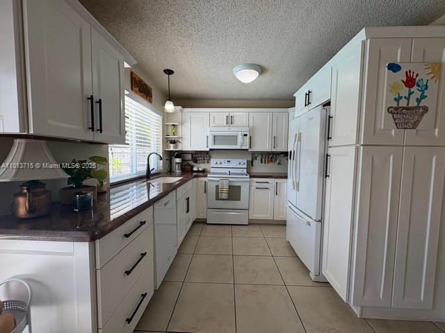 13324 SW 100th Ter, Miami, FL 33186 - kitchen featuring white appliances, a sink, dark countertops, white cabinetry, and a textured ceiling