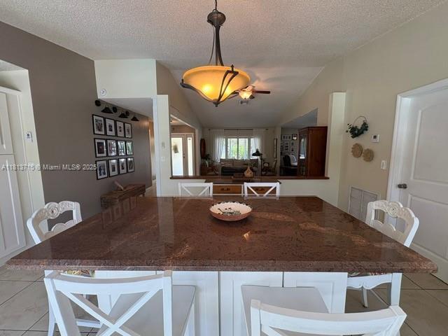13324 SW 100th Ter, Miami, FL 33186 - kitchen with lofted ceiling, light tile patterned floors, a kitchen bar, a textured ceiling, and pendant lighting