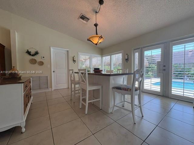 13324 SW 100th Ter, Miami, FL 33186 - kitchen featuring dark countertops, a breakfast bar area, a textured ceiling, vaulted ceiling, and light tile patterned flooring