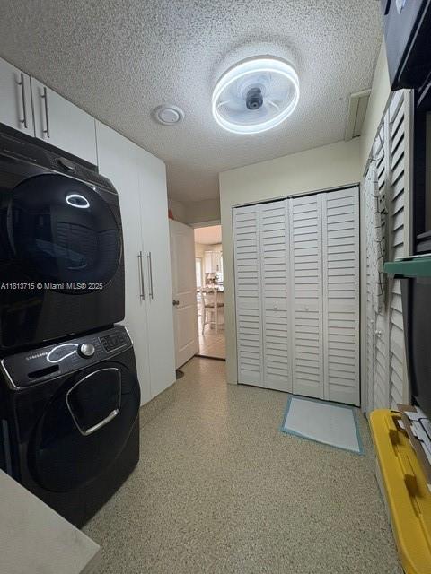 13324 SW 100th Ter, Miami, FL 33186 - laundry room with stacked washer and clothes dryer, cabinet space, and a textured ceiling