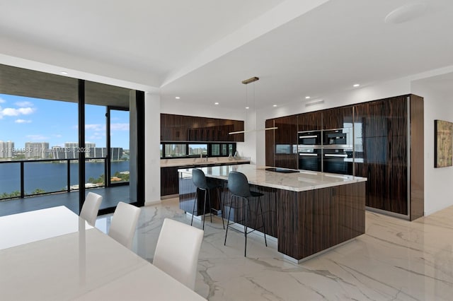 18555 Collins Ave Unit 1703, Sunny Isles Beach, FL 33160 - kitchen featuring modern cabinets, dark brown cabinets, recessed lighting, a water view, and a breakfast bar
