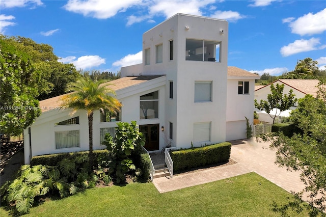 6320 Dolphin Dr, Coral Gables, FL 33158 - rear view of property featuring stucco siding, decorative driveway, a lawn, and a garage