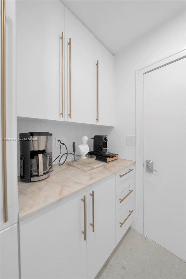 6320 Dolphin Dr, Coral Gables, FL 33158 - kitchen featuring white cabinets, light stone counters, and decorative backsplash