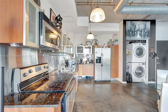 10 SW S River Dr Unit Ph108, Miami, FL 33130 - kitchen featuring appliances with stainless steel finishes, stacked washing machine and dryer, a sink, finished concrete flooring, and dark countertops