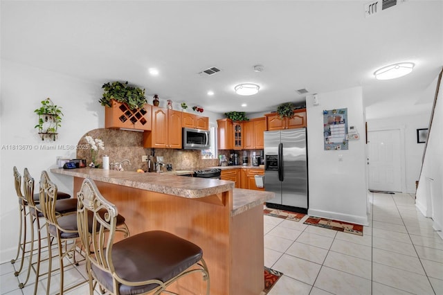 401 SW 109th Ave Unit 26, Sweetwater, FL 33174 - kitchen with appliances with stainless steel finishes, a peninsula, tasteful backsplash, glass insert cabinets, and a kitchen bar