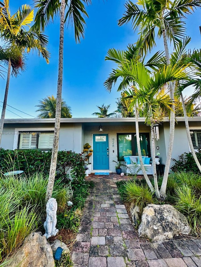 928 NE 18th Ct, Fort Lauderdale, FL 33305 - doorway to property with stucco siding, covered porch, and an outdoor hangout area