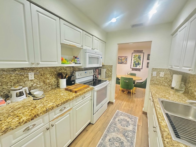 928 NE 18th Ct, Fort Lauderdale, FL 33305 - kitchen featuring white appliances, tasteful backsplash, light wood-style flooring, white cabinets, and a sink