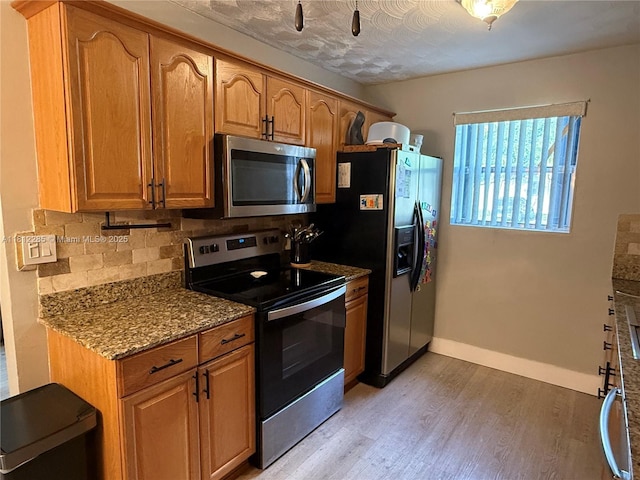 2430 N 61st Ter, Hollywood, FL 33024 - kitchen featuring appliances with stainless steel finishes, light wood-style floors, dark stone counters, tasteful backsplash, and brown cabinetry