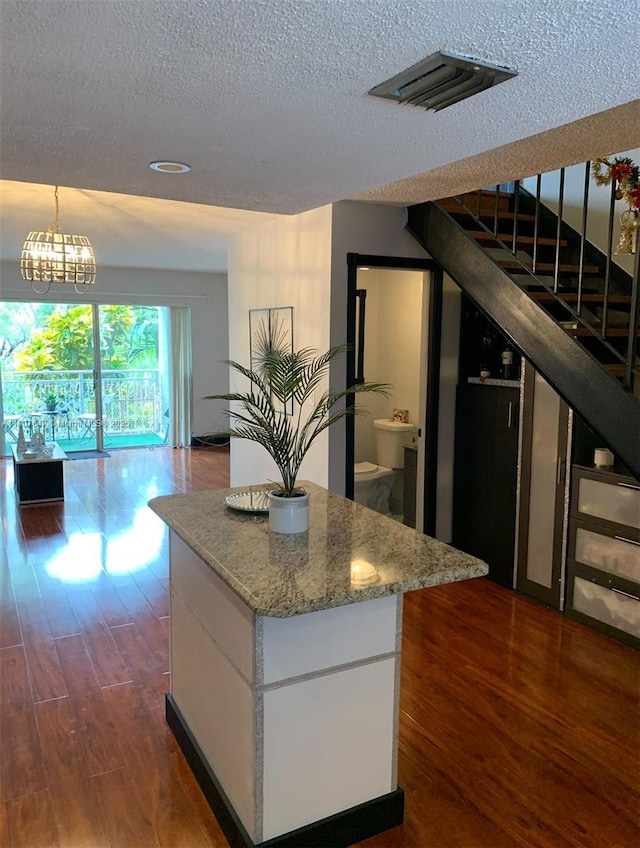 9351 Fontainebleau Blvd Unit B206, Miami, FL 33172 - kitchen featuring a textured ceiling, dark wood finished floors, open floor plan, light stone counters, and a kitchen island