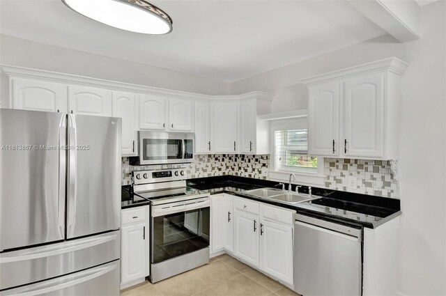 276 NE 90th St, El Portal, FL 33138 - kitchen featuring stainless steel appliances, dark countertops, white cabinetry, a sink, and backsplash