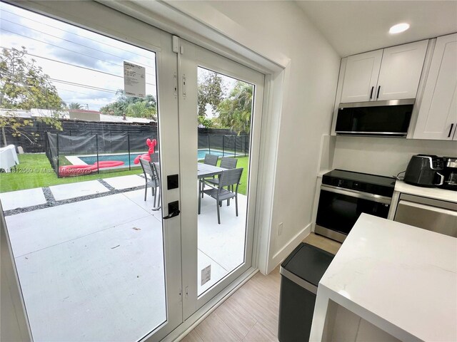 1451 NE 155th Ter, North Miami Beach, FL 33162 - kitchen with stainless steel appliances, white cabinetry, recessed lighting, and light wood-style floors