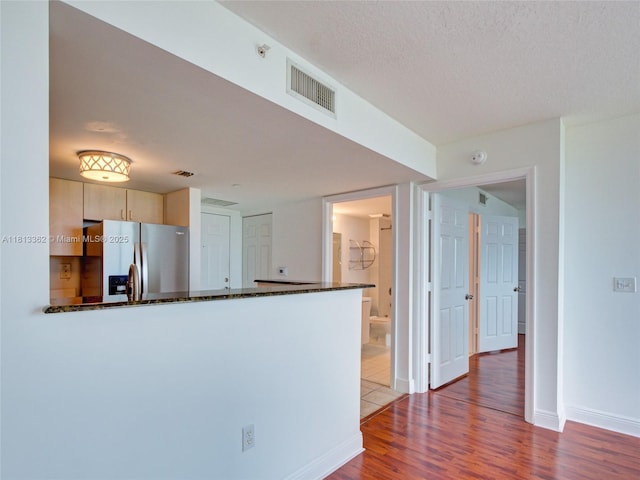 3000 Coral Way Unit 715, Miami, FL 33145 - kitchen featuring stainless steel fridge with ice dispenser, a peninsula, dark stone countertops, wood finished floors, and light brown cabinets